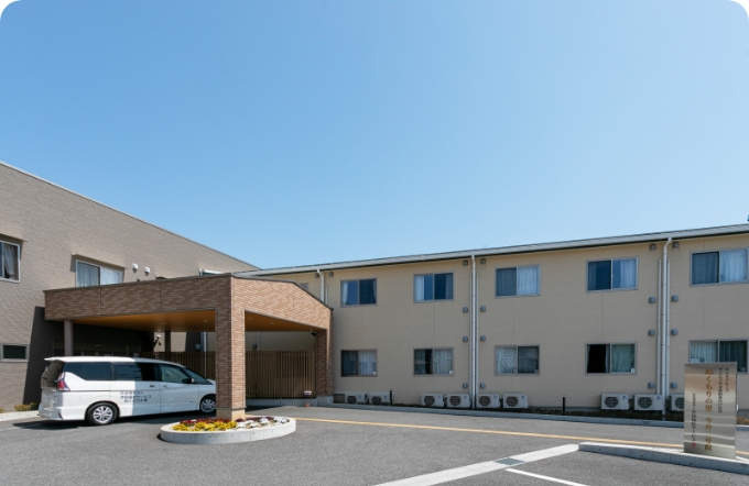 介護施設の建物外観。車寄せ付きの現代的な外観で清潔感がある。