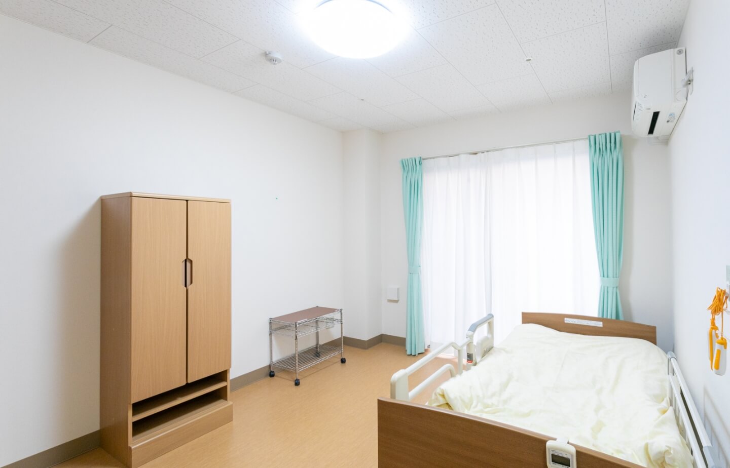 介護施設の居室。ベッド・クローゼット・窓が備わった明るい個室空間。